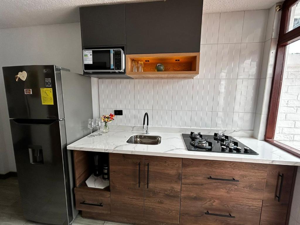 a kitchen with a sink and a refrigerator at Mamitas House! Mini Suit Privada Junto al Metro de Quito in Quito