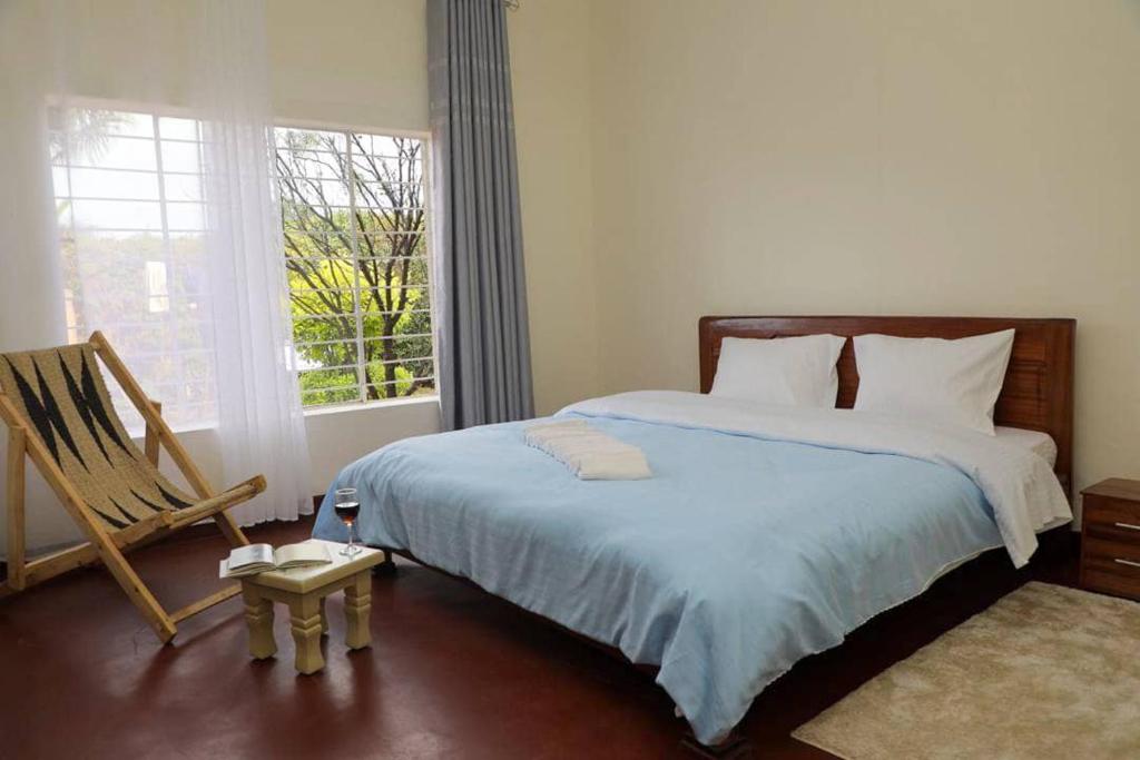 1 dormitorio con 1 cama, 1 silla y 1 ventana en Inkindi House en Kigali