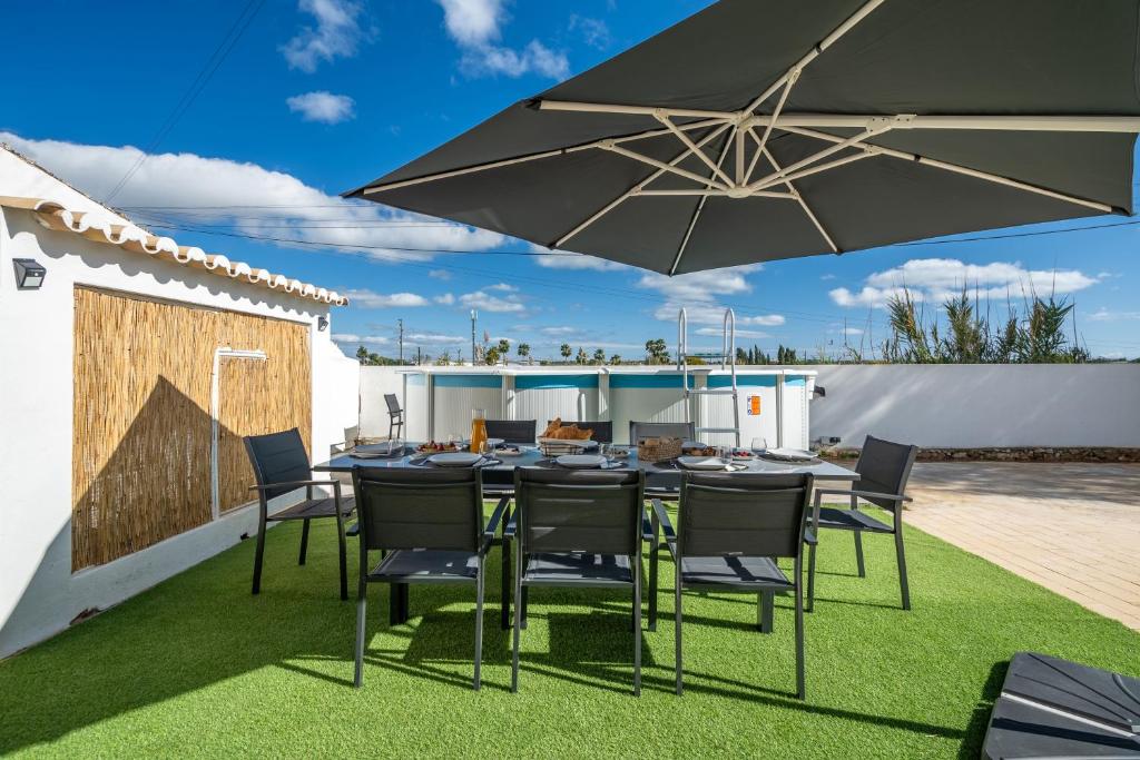 a patio with a table and chairs and an umbrella at Host Wise - Sunny Spacious House - Terrace & Free Parking in Lagoa