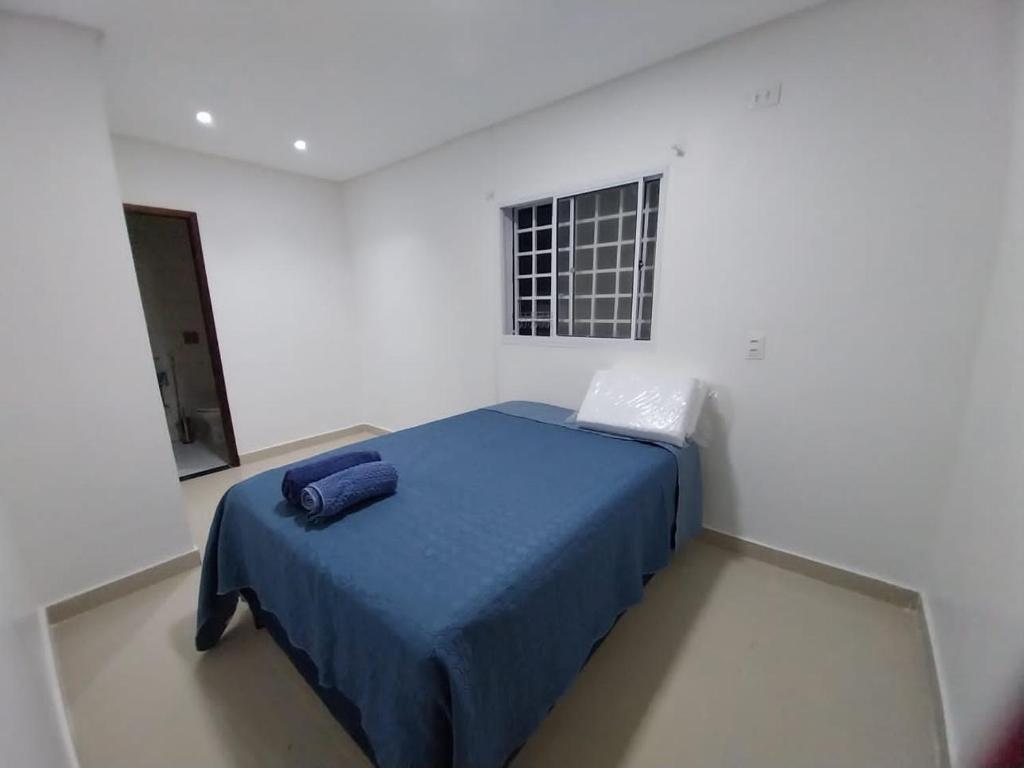 Casa Pitanga في أوليندا: غرفة نوم بسرير ازرق في غرفة بيضاء