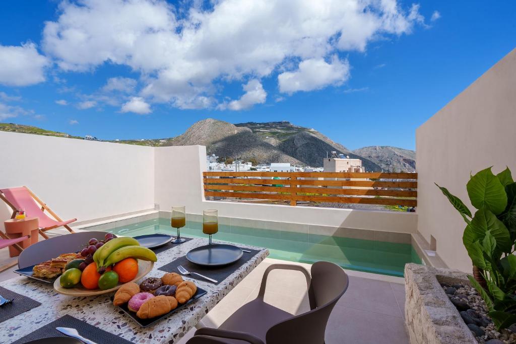 a table with fruit and wine glasses on a balcony at Sugarwhite Suites with Private not Heated Pool in Emporio Santorini