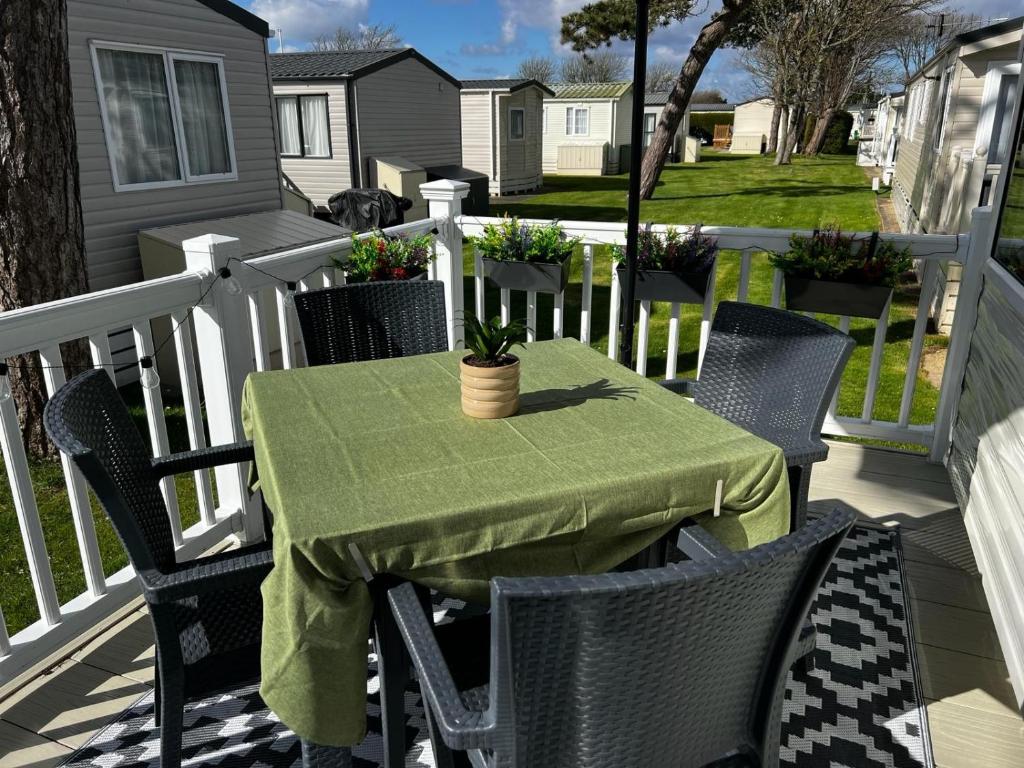 a table and chairs on a porch with a green tablecloth at Fabulous Beach Getaway Naish Est near New Forest in New Milton