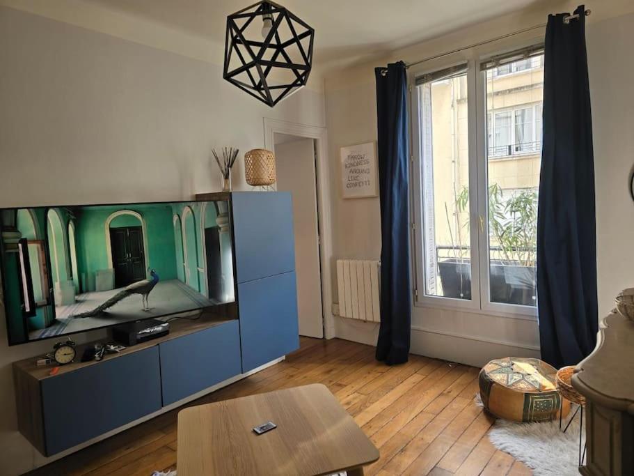 ein Wohnzimmer mit einem TV und einem großen Fenster in der Unterkunft Charmant 3 pièces de 41m² in Saint-Mandé