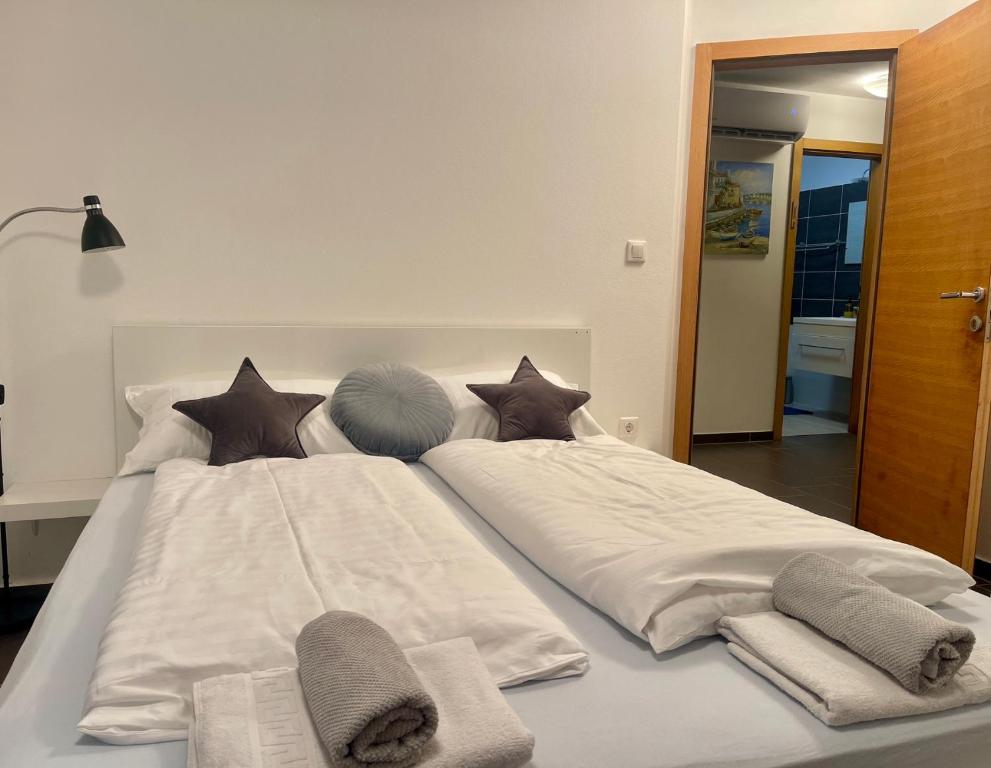 duże białe łóżko z poduszkami i ręcznikami. w obiekcie V&V Medulin pool and sea w Medulinie