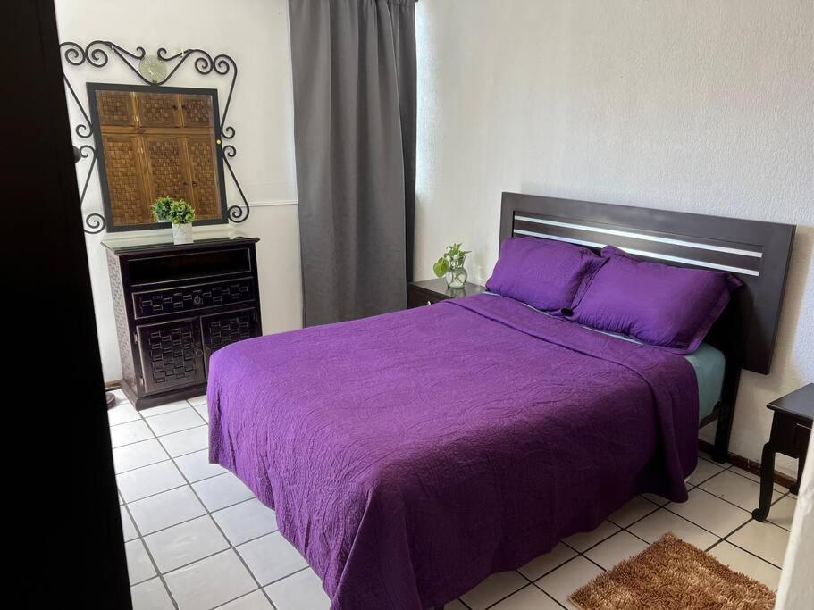 1 dormitorio con cama morada y chimenea en Caza en zona residencial en Uruapan del Progreso