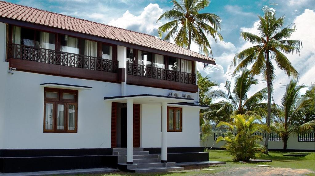 a white house with palm trees in the background at Acquabey Surf Villa in Matara