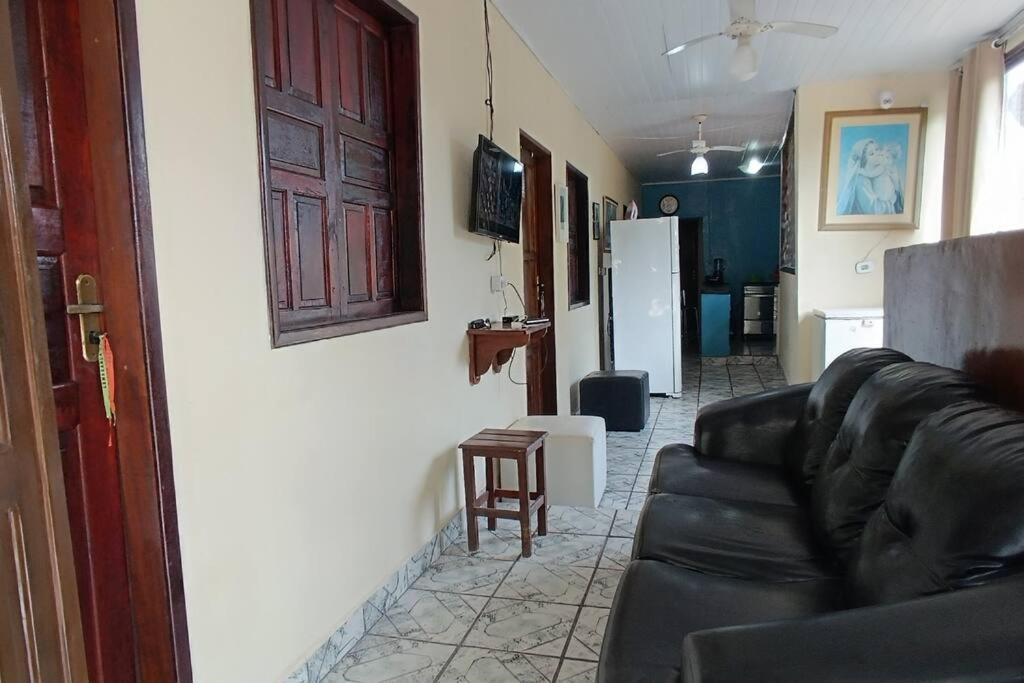 ein Wohnzimmer mit einem schwarzen Ledersofa und einem Kühlschrank in der Unterkunft Casa para Família in Porto Seguro