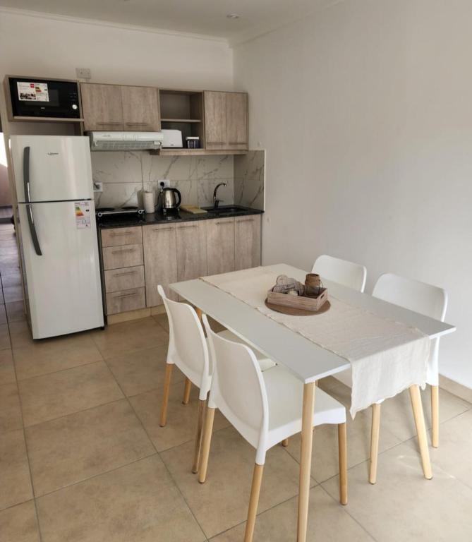 uma cozinha com uma mesa e cadeiras e um frigorífico em Junidep Alquiler Temporario - Deptos Nuevos ! em Junín