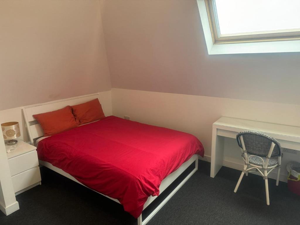 a small bedroom with a red bed and a chair at Stay Inn East West in Aberdeen