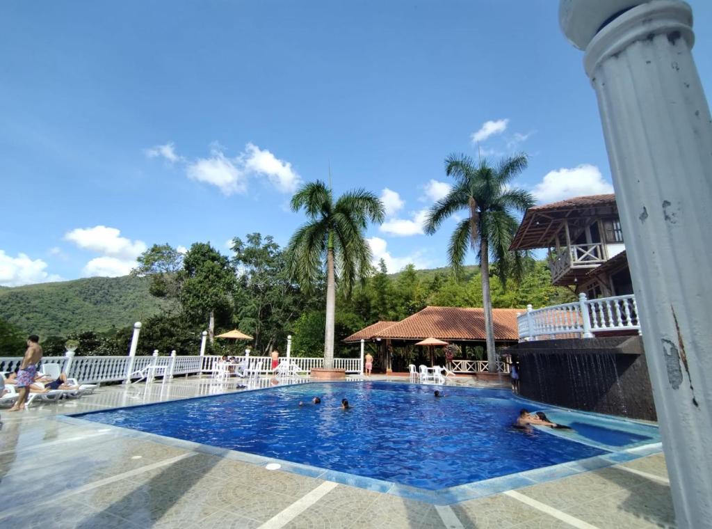 a pool at a resort with palm trees at Hotel campestre los Arrieros in Guaduas