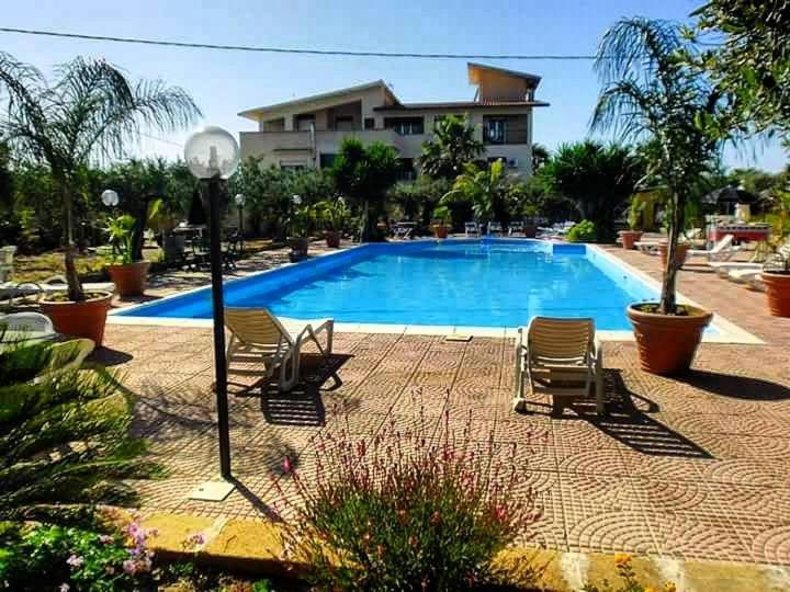 una piscina con sillas y una casa en el fondo en Residence Sciacca Hope, en Cartabubbo