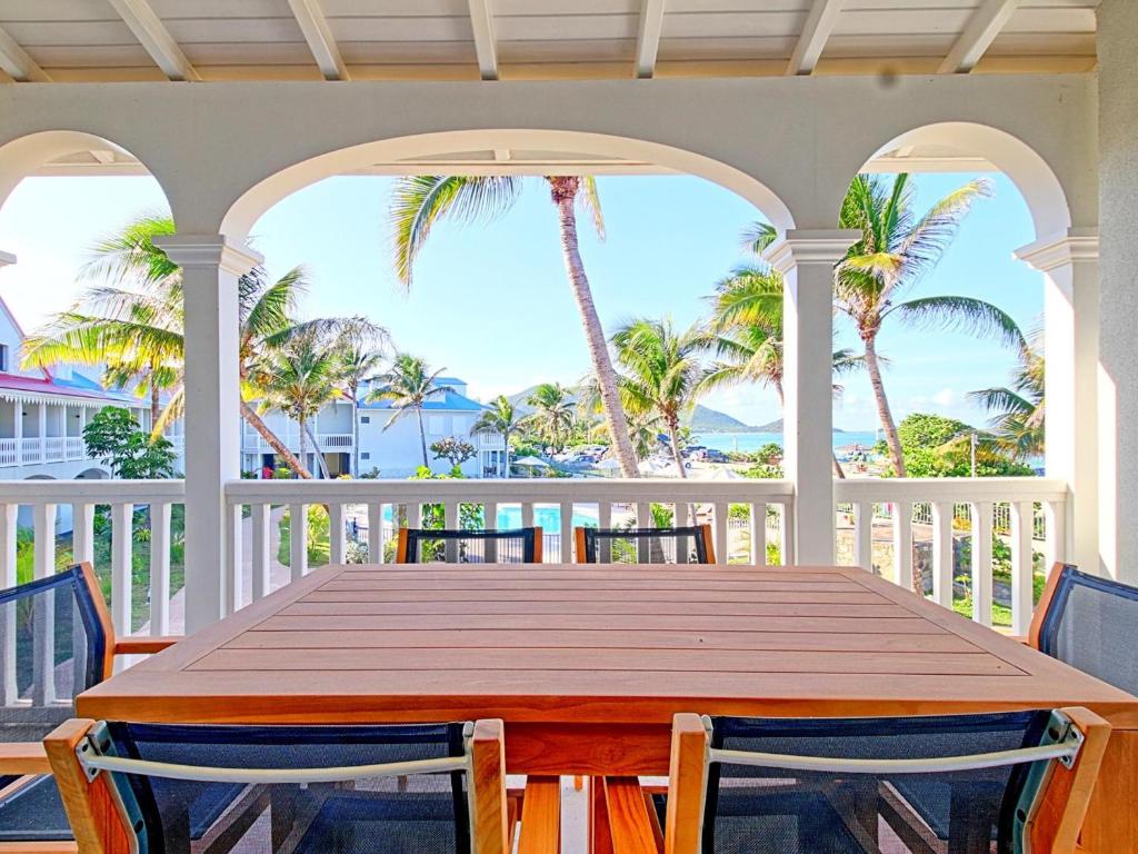 a wooden table on a porch with palm trees at Appartement Saint-Martin , 3 pièces, 4 personnes - FR-1-734-41 in Saint Martin