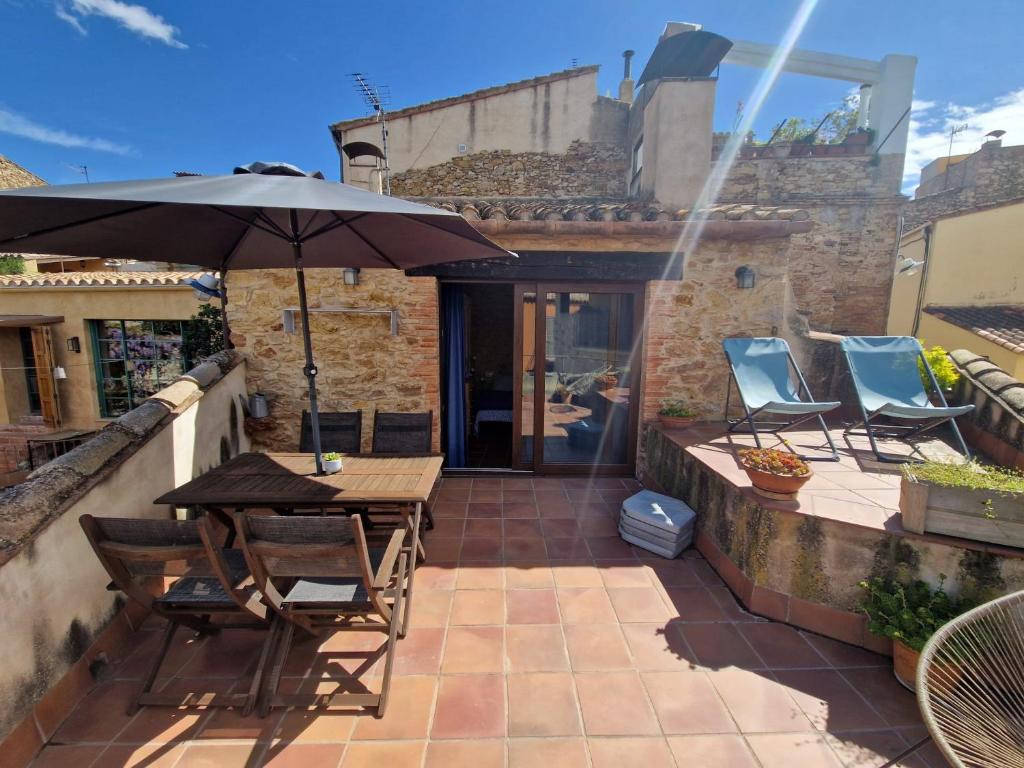 une terrasse avec une table, des chaises et un parasol dans l'établissement Can Bruguera de Fonteta, à Fonteta