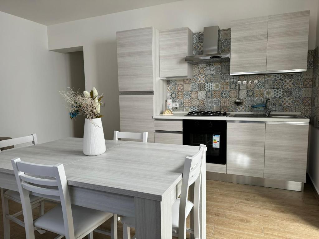 een keuken met een houten tafel en witte stoelen bij Za Nedda Home in Fiumefreddo di Sicilia