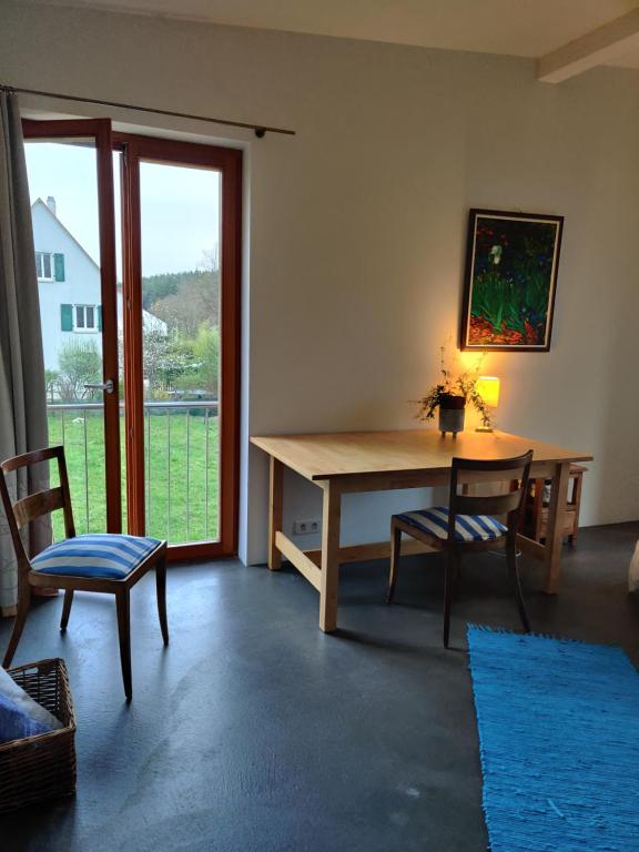 Petit nid en Alsace studio indépendant avec salle de douche privative في Buschwiller: غرفة معيشة مع طاولة خشبية وكرسيين