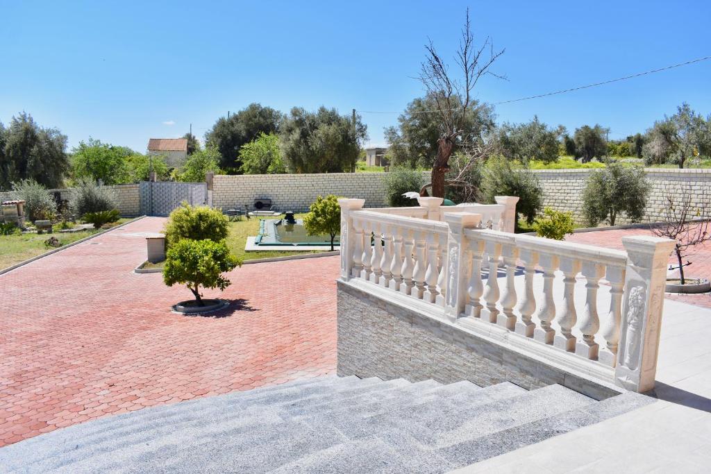 a white fence in a garden with a tree at Villa Caruso in Avola