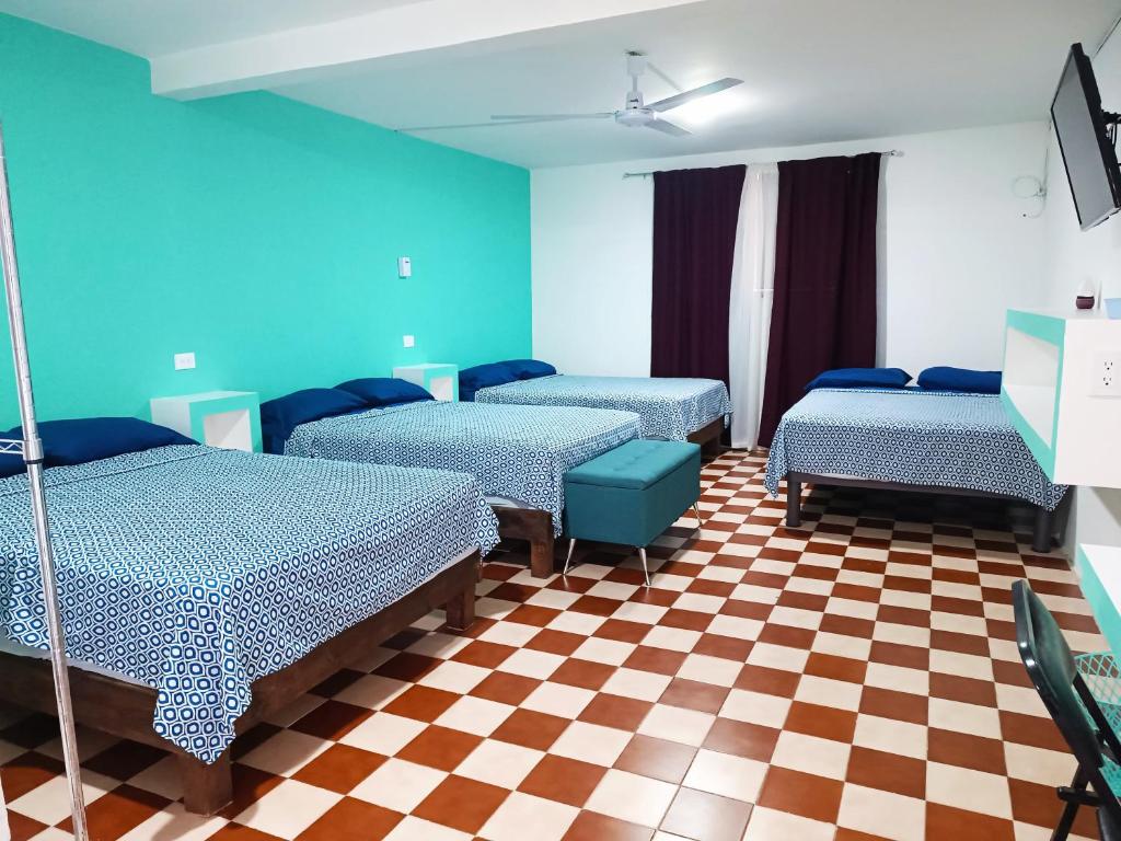 a room with four beds and a checkered floor at Hotel Posada Los Faroles Atlixco in Atlixco