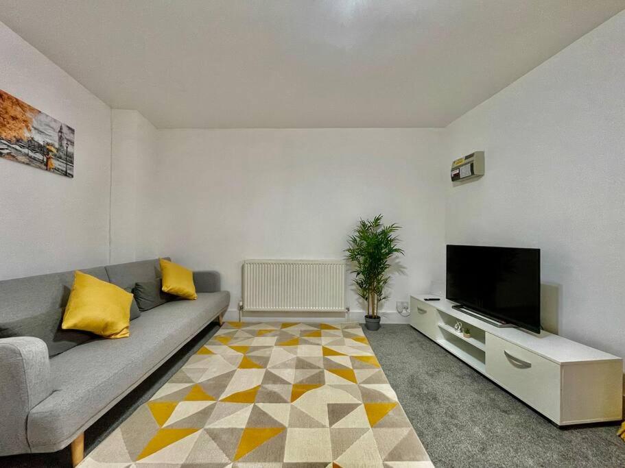 ein Wohnzimmer mit einem Sofa und einem Flachbild-TV in der Unterkunft Modern Cosy 1 Bed Ilford Home - Free Parking in Ilford