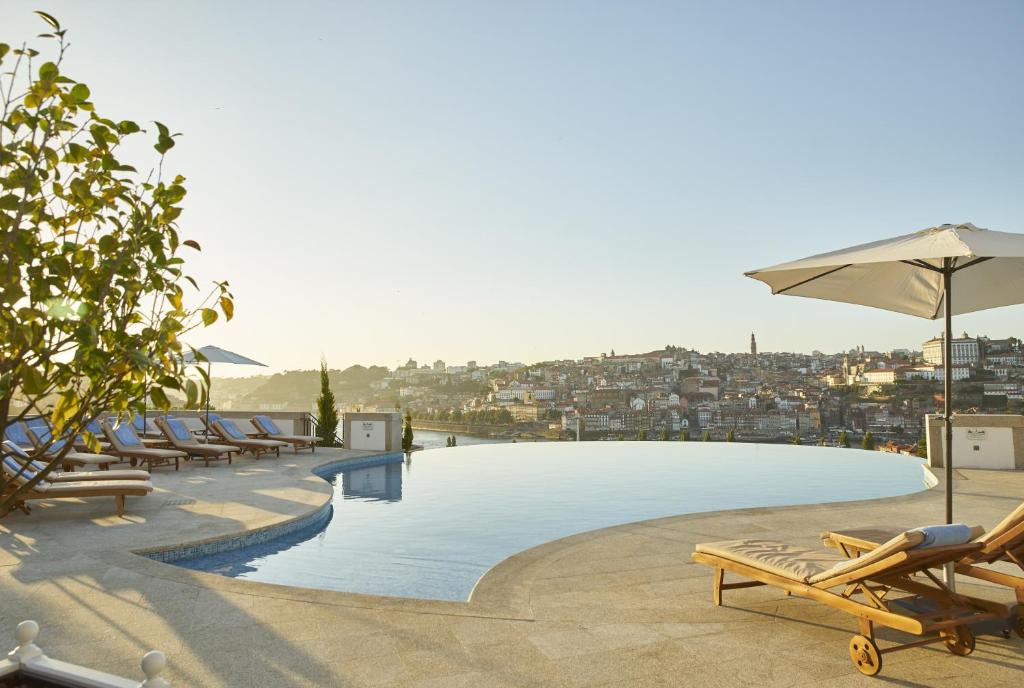 - une grande piscine avec des chaises et un parasol dans l'établissement The Yeatman, à Vila Nova de Gaia