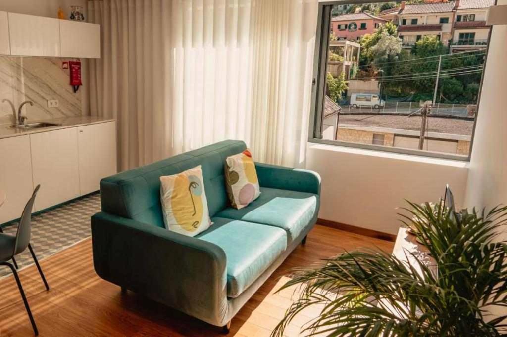 un soggiorno con divano verde e finestra di Gerês Adelaide Studios a Geres