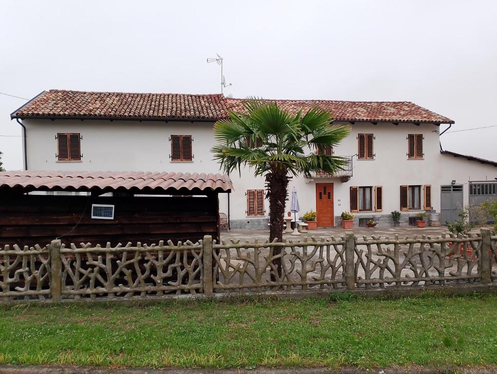 ein Haus und eine Palme hinter einem Zaun in der Unterkunft La vigna in Costigliole dʼAsti