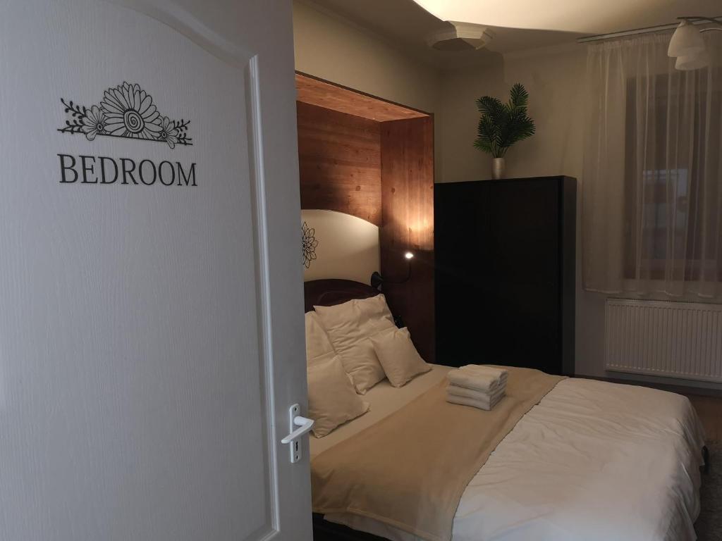 a bedroom with a bed with a sign on the door at Levendula Apartman in Makó