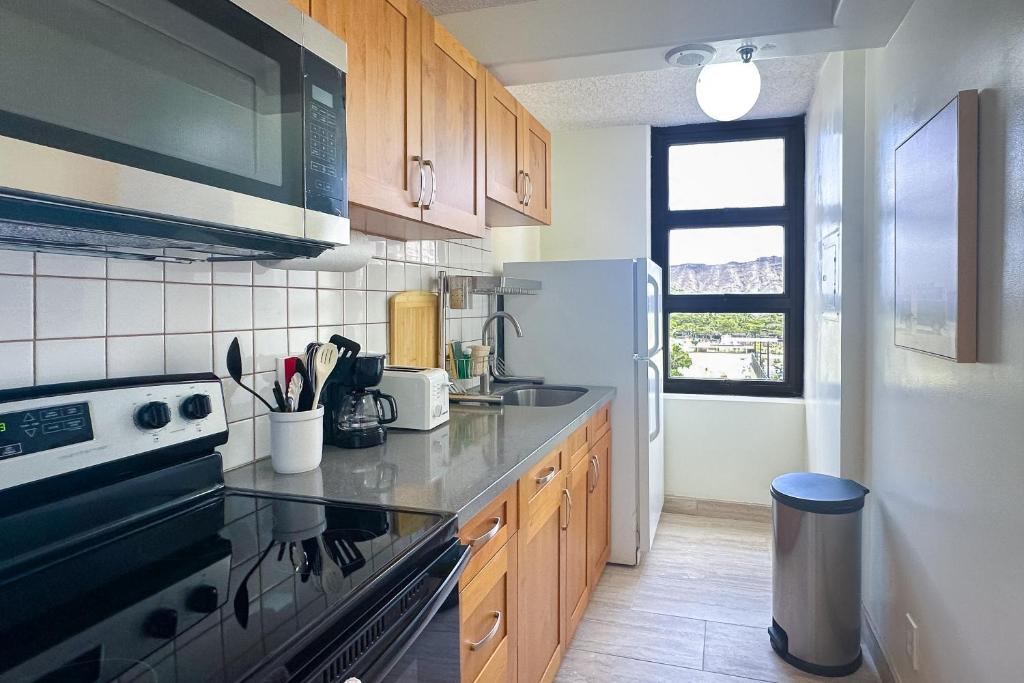 a kitchen with a stove and a refrigerator at Waikiki Banyan 913 in Honolulu