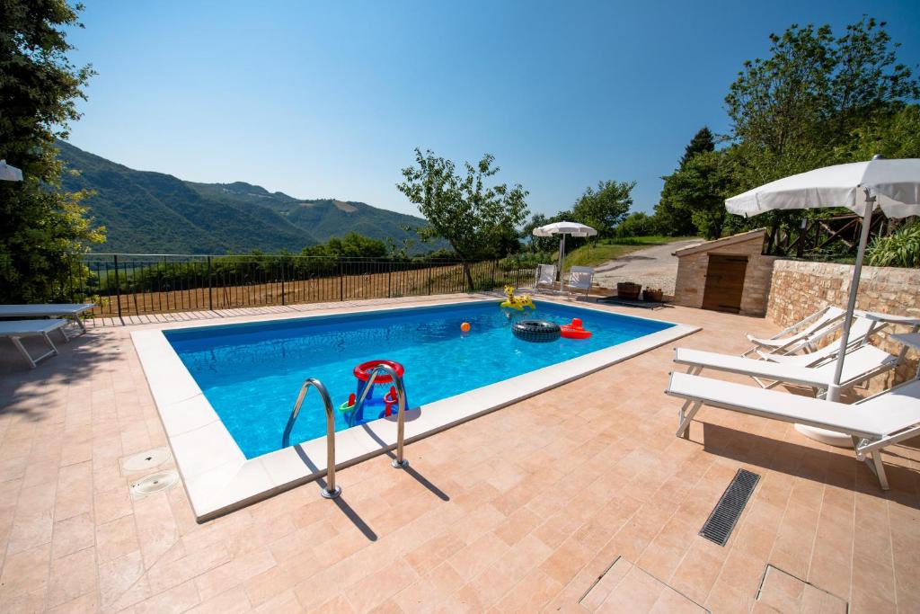 una piscina con 2 sillas y una sombrilla en Casetta in Pietra, en Acqualagna