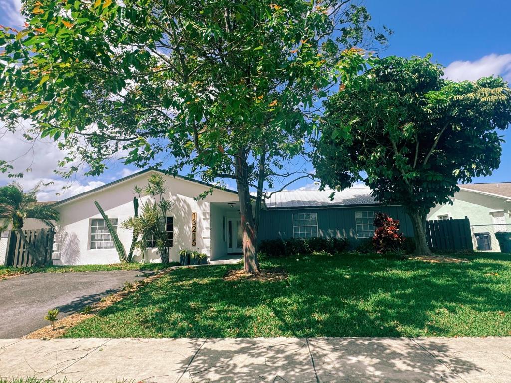 une maison avec un arbre dans la cour avant dans l'établissement Family Friendly 4Bedroom, 3Bathroom, Hot Tub, BBQ, near Everglades, Miami MetroZoo, à Homestead