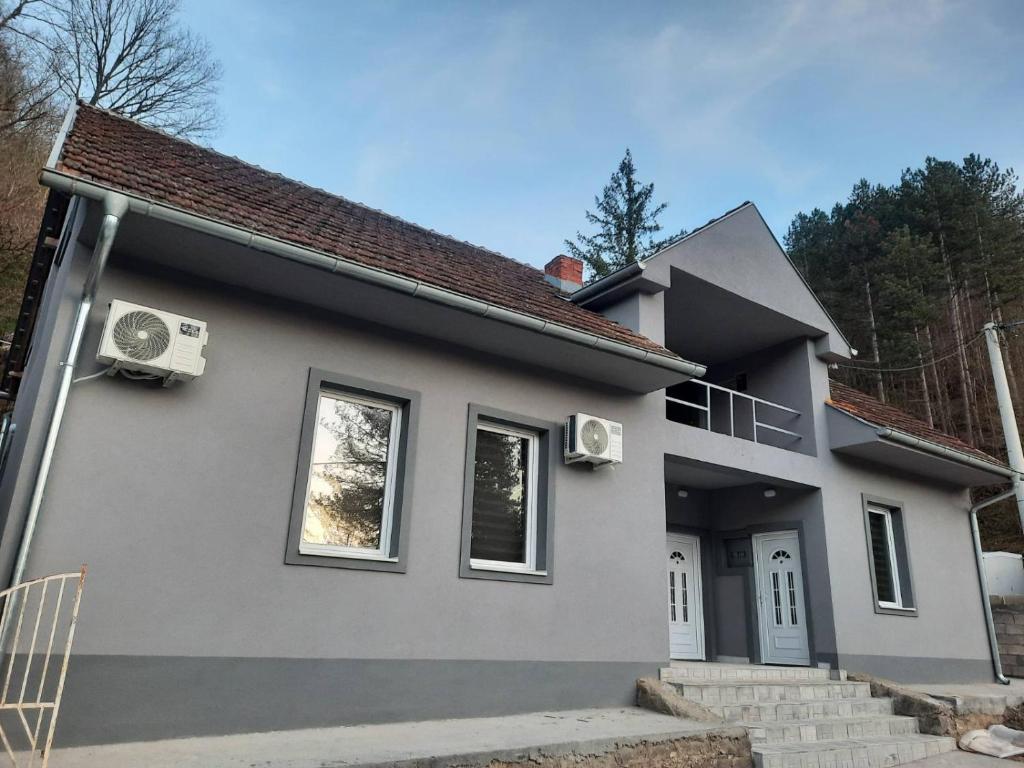 una piccola casa grigia con di Apartmani Ćosić - Kuršumlijska banja a Kursumlijska Banja