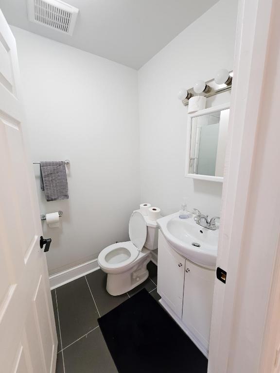 a white bathroom with a toilet and a sink at Ottawa Downtown Cozy Guesthouse in Ottawa