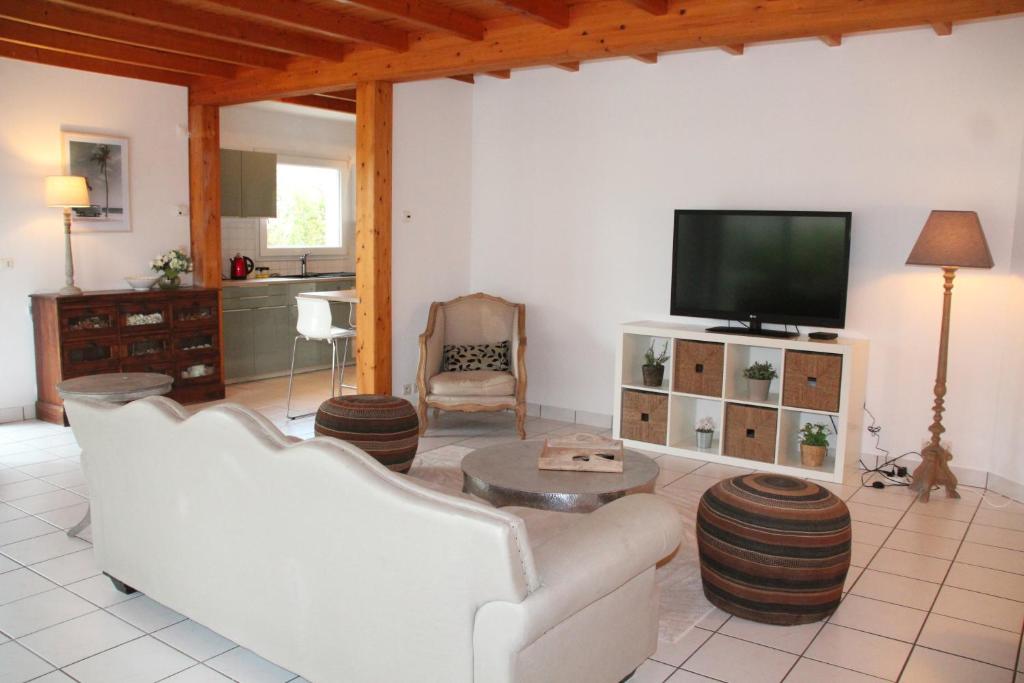 uma sala de estar com mobiliário branco e uma televisão de ecrã plano em Ty Traezh - La plage à 100m em Santec