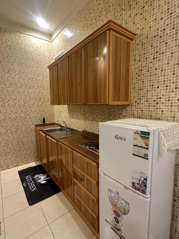 uma cozinha com um frigorífico branco e armários de madeira em شقة ب الحمراء بدخول ذاتي em Riyadh