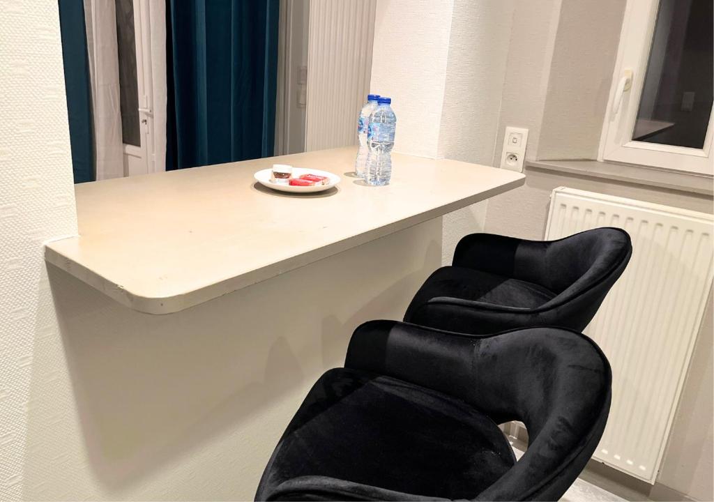 two black chairs sitting next to a table with a bottle of water at Le Charme D&#39;Antan in Évreux