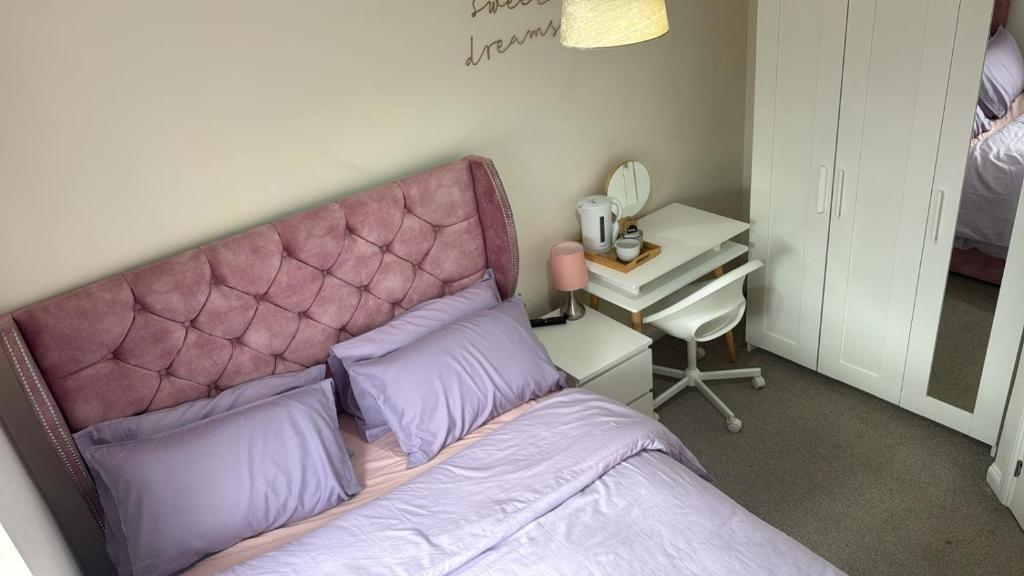 a bed with a pink headboard in a bedroom at Glamshouse in Bushbury