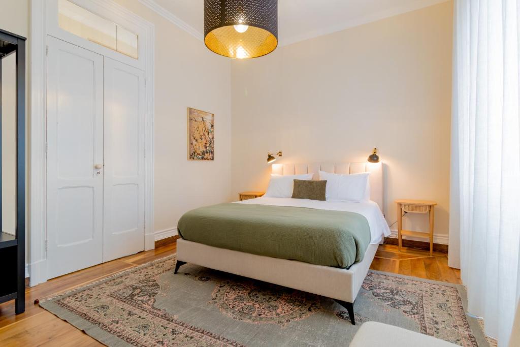 a white bedroom with a bed and a rug at Canto do Atlantico - City Centre in Ponta Delgada