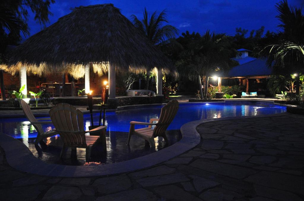 two chairs and a swimming pool at night at Surf Sanctuary in El Limón