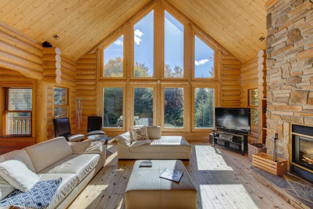 uma grande sala de estar com uma grande lareira de pedra em Fiddler Lake Resort Chalet Deer 59 em Mille-Isles