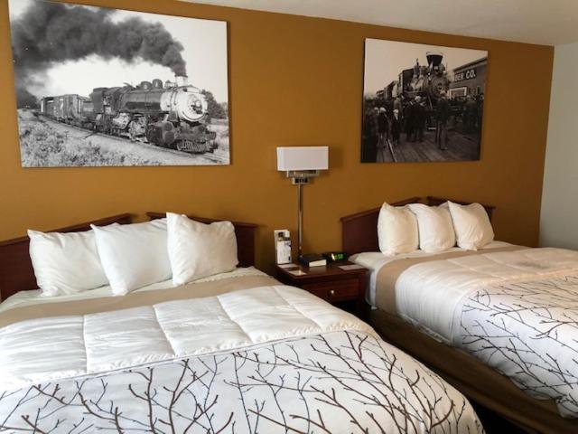 a hotel room with two beds and a train painting on the wall at Heritage Inn Express in Marysville