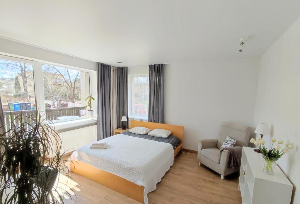 een slaapkamer met een bed, een stoel en een raam bij Miegu - Apartments in Druskininkai