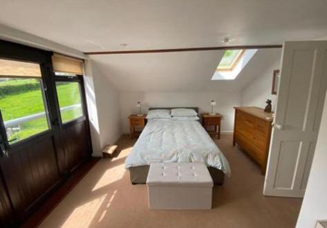 a bedroom with a bed and a large window at Trelowen Cottage in Callington