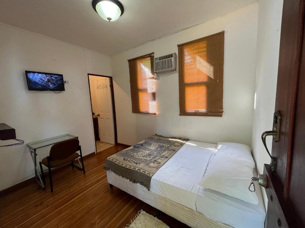 a bedroom with a bed and a desk and two windows at La Perla de Cobano in Puntarenas