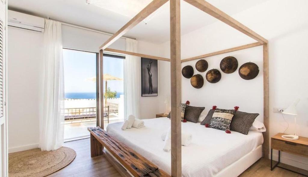 a bedroom with a canopy bed with a view of the ocean at Victoria Sunset Suites in Port des Torrent