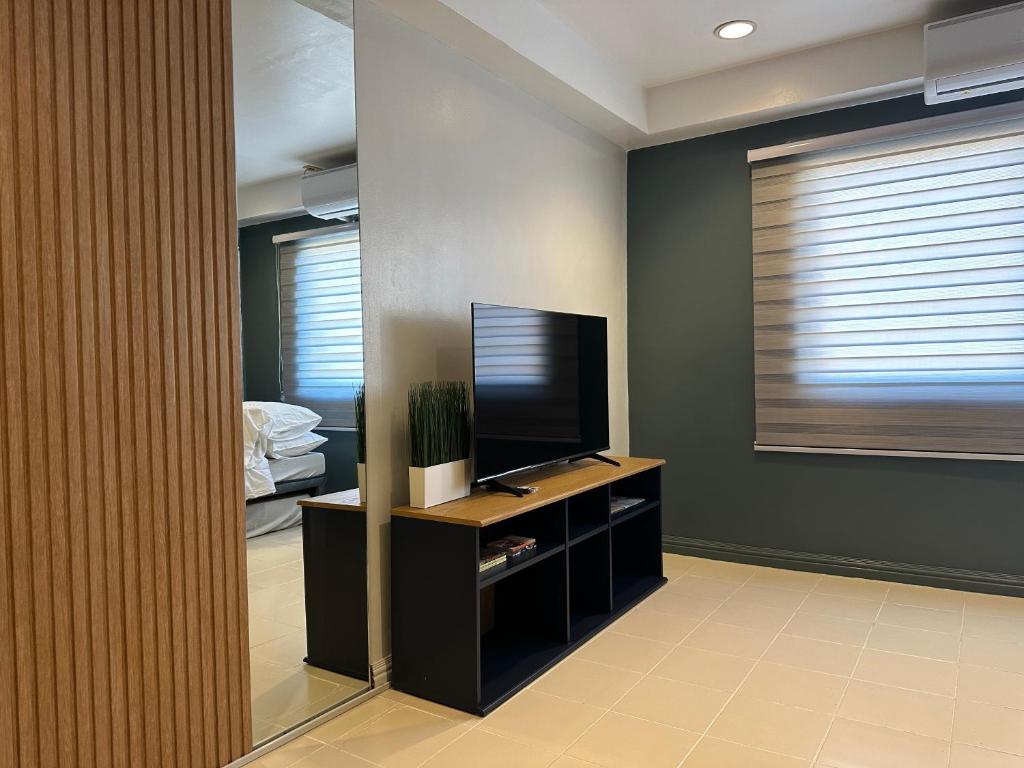 CRIB 217 SUBIC BAY - Modern Fresh Condo في اولونجابو: غرفة معيشة فيها تلفزيون وغرفة نوم