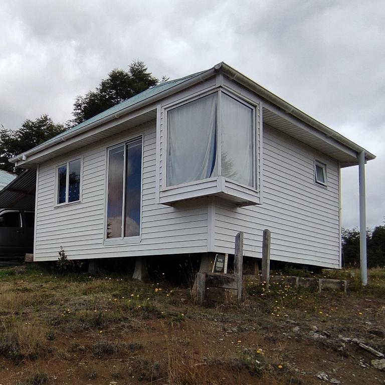 a small white house sitting on top of a field at Cabaña Carpintero negro in Dalcahue