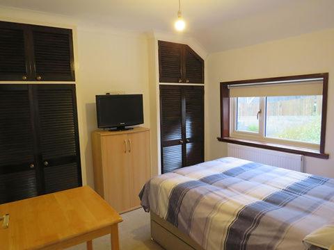 een slaapkamer met een bed en een flatscreen-tv bij Hillside in Llanelli