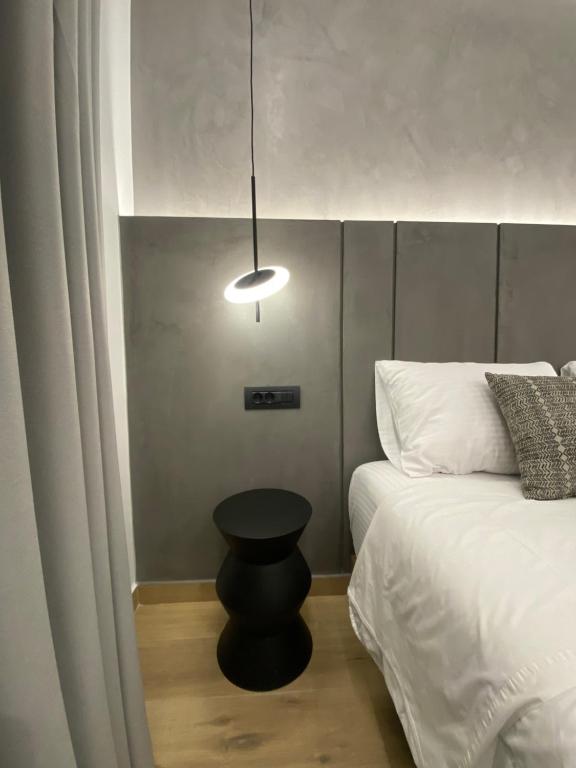 a bedroom with a bed with a black stool next to it at Tramonto Maisonettes & Suites in Parga