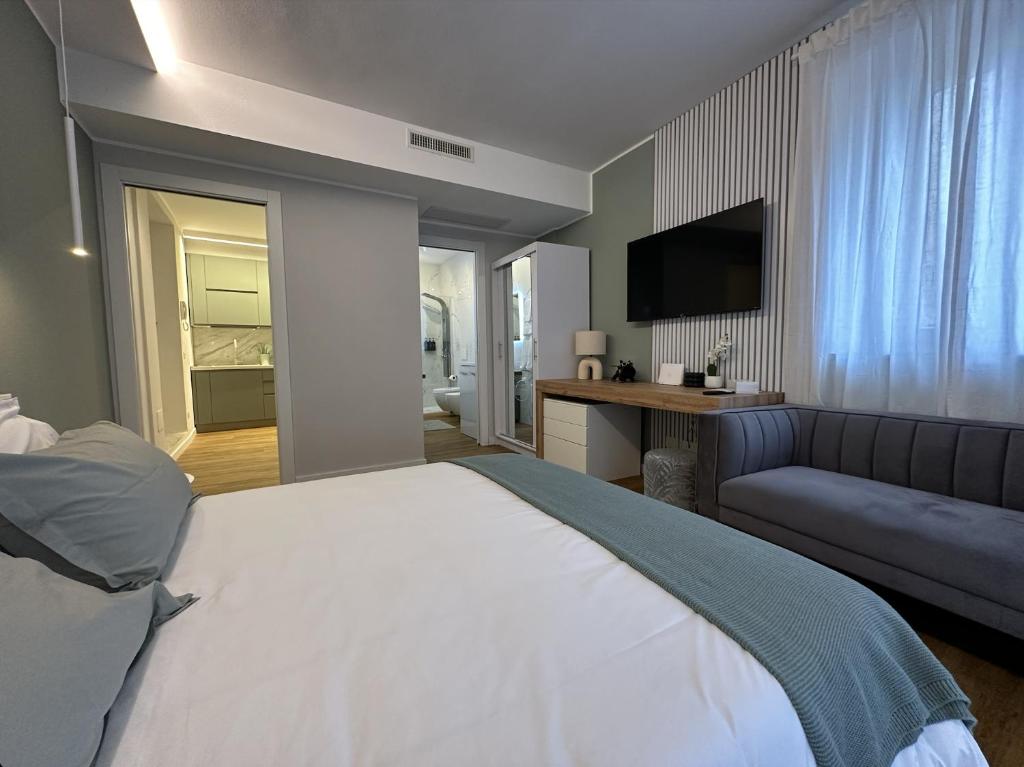 1 dormitorio con 1 cama grande y 1 sofá en The Captain's Apartments SIROCCO - CITY CENTER Leonardo Academy, en Sesto Calende