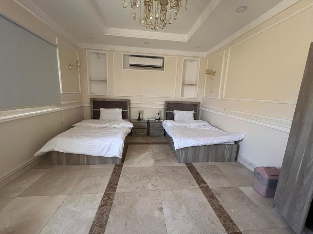 a room with two beds in it with a chandelier at فيلا سكنية فاخرة in AlUla