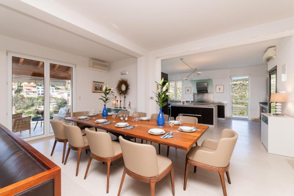 a dining room and kitchen with a large wooden table and chairs at VILLA PHILIPPA - luxurious five-room villa on the island of BRAČ - idyllic location right by the sea - incredible view of the sea bay - VIP services - BURALUX properties in Sutivan
